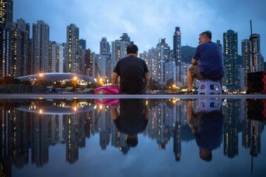 Fishermen are reflected in a puddle as Hong Kong's skyline looks in front of them. Despite a contracting economy, existing house prices in Hong Kong have risen 1.2 per cent this year, according to Centaline. EPA
