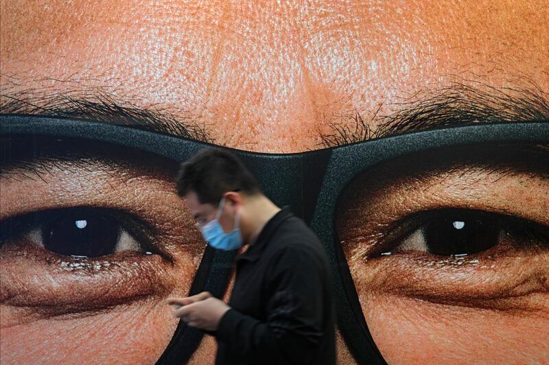 A man wearing a face mask to help curb the spread of the coronavirus walks by an advertisement at a subway station in Beijing. AP