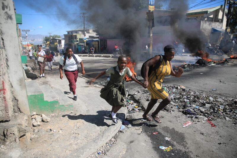 People flee as protesters and police clash in Port-au-Prince, Haiti. AP