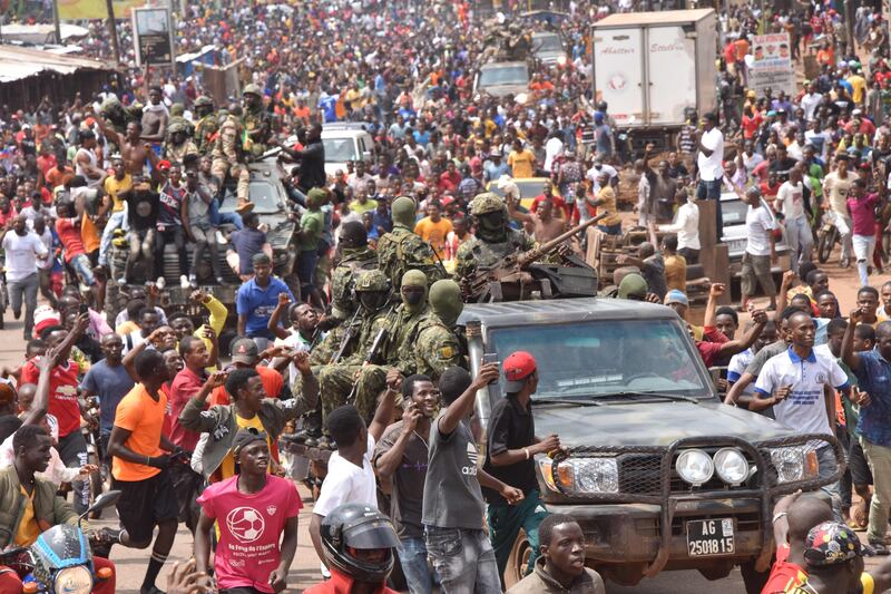 People celebrate in the streets with members of Guinea's armed forces after the arrest of Guinea's president, Alpha Conde, in a coup d'etat in Conakry.  Guinean special forces seized power in a coup on September 5, arresting the president and imposing an indefinite curfew in the poor west African country.  AFP