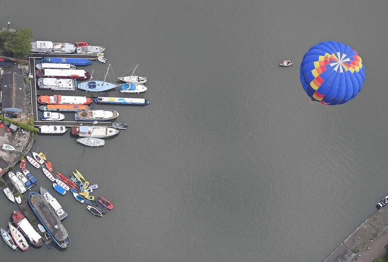 A balloon flies over moored boats during a mass take off at the annual Bristol hot air balloon festival in Bristol, Britain.  Reuters