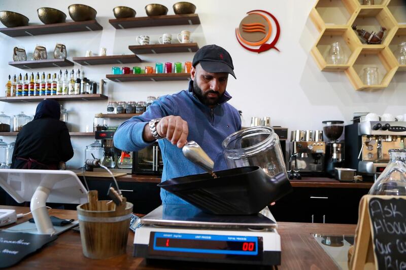 In this Jan. 9, 2018, photo, Ibrahim Alhasbani, owner of Qahwah House, a cafe that serves coffee made from beans harvested on his family's farm in Yemen's mountains, measures coffee beans in Dearborn, Mich. Yemeni have been coming to the U.S. for more than a century _ especially since the 1960s _ but in recent years they have been planting stronger roots, raising their profile and looking outward _ opening upscale restaurants and cafes and running for political office. And, in cases like Alhasbani, they are making Yemeni culture a key part of the business proposition. (AP Photo/Carlos Osorio)