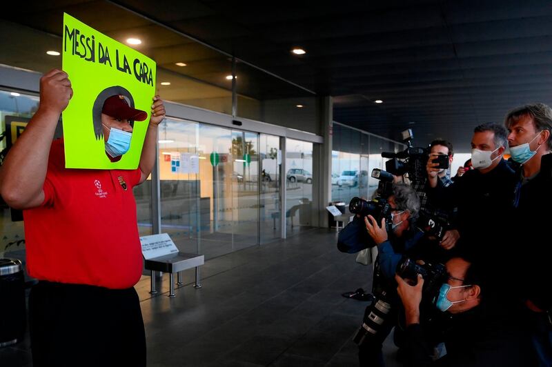 A Barcelona fan holds a banner that reads "Messi da la cara" (Messi take your responsibility) as Jorge Messi arrives at the airport in Barcelona. AFP