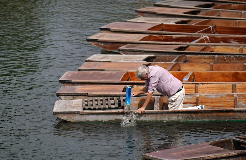 Rainwater is bailed out of punts on the River Cam in Cambridge