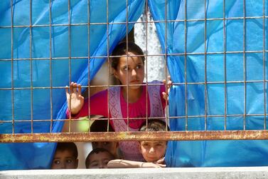 Syrian refugee children look through a fence at a refugee camp. AFP