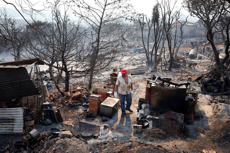 A resident inspects his home, which was completely destroyed by fire in Dervenochoria. EPA