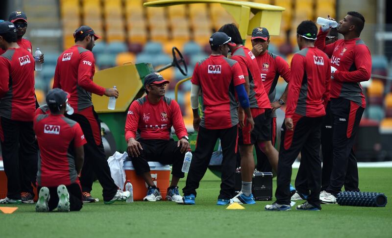 Former Pakistani fast bowler and United Arab Emirates (UAE) coach Aaqib Javed (5th L-seated) looks on as cricketers take a break during a training session ahead of 2015 Cricket World Cup Pool B match between Ireland and UAE at the Gabba cricket stadium in Brisbane on February 24, 2015.  AFP PHOTO / INDRANIL MUKHERJEE  
-- IMAGE RESTRICTED TO EDITORIAL USE - STRICTLY NO COMMERCIAL USE-- (Photo by INDRANIL MUKHERJEE / AFP)