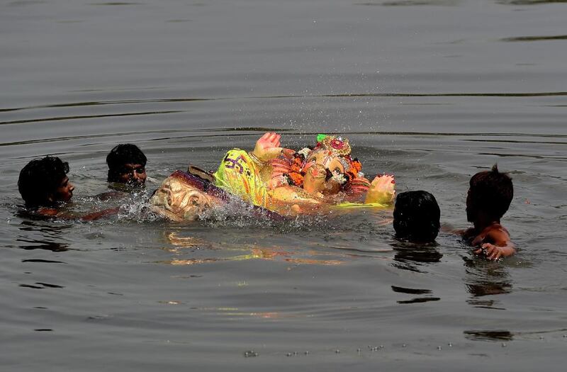 Devotees immerse an idol of elephant-headed Hindu God, Lord Ganesh in the river Yamuna in New Delhi.  Money Sharma / AFP