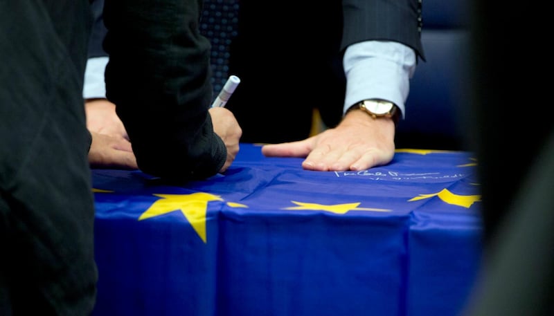 Eurogroup finance ministers sign an EU flag during a round table meeting of eurogroup finance ministers in Luxembourg, Monday, Oct. 9, 2017. Wolfgang Schaeuble, the long-time German finance minister, is attending his final meeting of his peers in the 19-country eurozone on Monday. (AP Photo/Virginia Mayo)