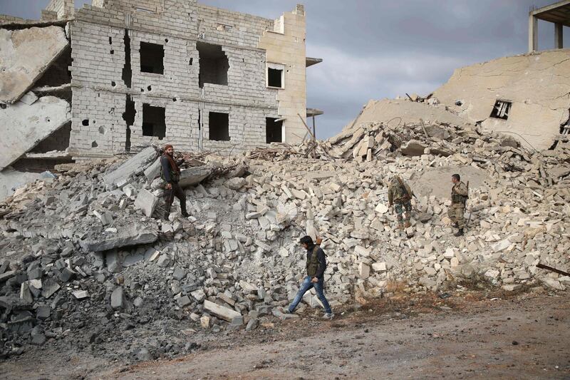 TOPSHOT - Syrian rebel-fighters from the National Liberation Front (NLF) walk through the rubble of a building destroyed by a reported air strike from the day before in the rebel-held al-Rashidin district of western Aleppo's countryside near Idlib province, on November 26, 2018. Air strikes hit the edges of Syria's last major rebel stronghold west of Aleppo on November 25, the Britain-based Syrian Observatory for Human Rights monitor said a day after an alleged toxic attack on the regime-held city. The SOHR said regime ally Russia "likely" carried out the air strikes on a planned buffer zone around the opposition bastion of Idlib, the first to hit the area since Moscow and rebel backer Ankara agreed to set up a demilitarised area around Idlib to prevent a massive regime attack to retake the area. / AFP / Aaref WATAD
