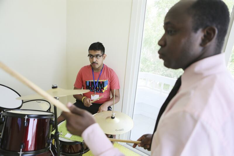 Varun Raina learns to drum from activity leader Samson Agibola at the Tender Hearts Arena in Dubai. Sarah Dea / The National