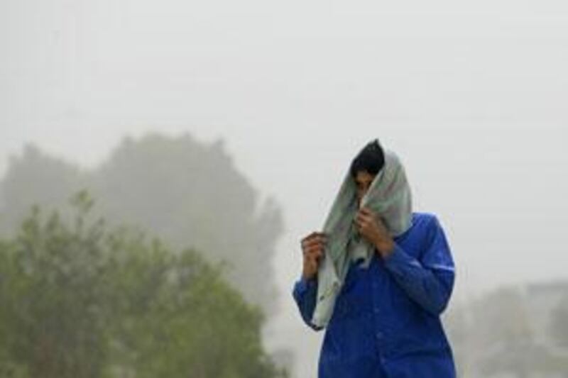 A man shields his face from a sand storm in Khalifa City A. Visibility was down to 1,000 metres in Abu Dhabi.