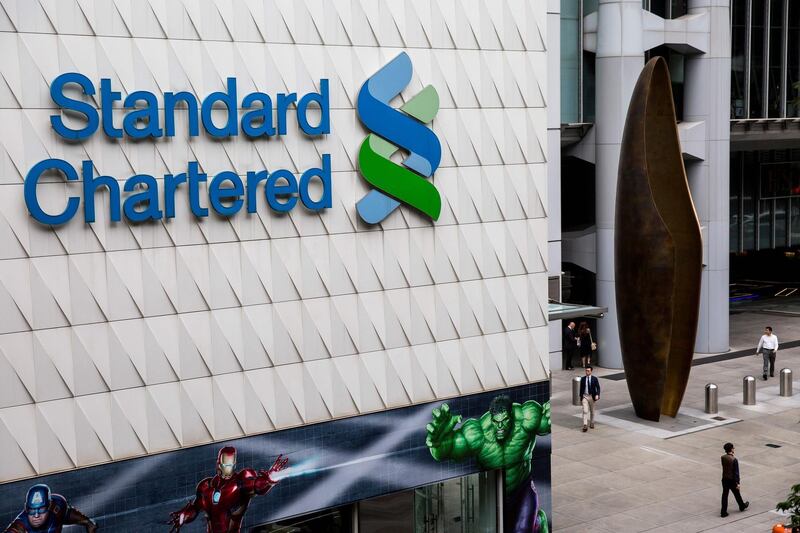 Pedestrians walk past Standard Chartered signage in the Central district of Hong Kong on August 2, 2017.
Standard Chartered's half-year results will be announced later in the day. / AFP PHOTO / Isaac LAWRENCE