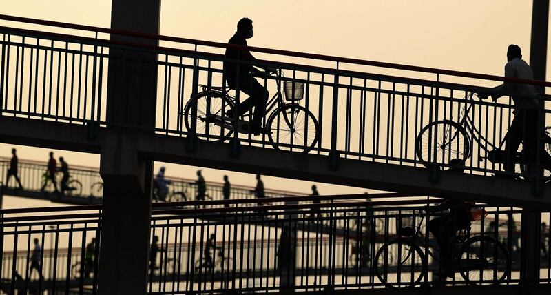 People walk or ride bicycles over a bridge, during the novel coronavirus pandemic crisis, in the Emirati city of Dubai. AFP