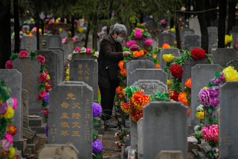 An elderly woman places flowers on a tomb during Qingming festival also known as Tomb Sweeping Day when family members visit their ancestral graves to clean up and burn offerings in Beijing. AP