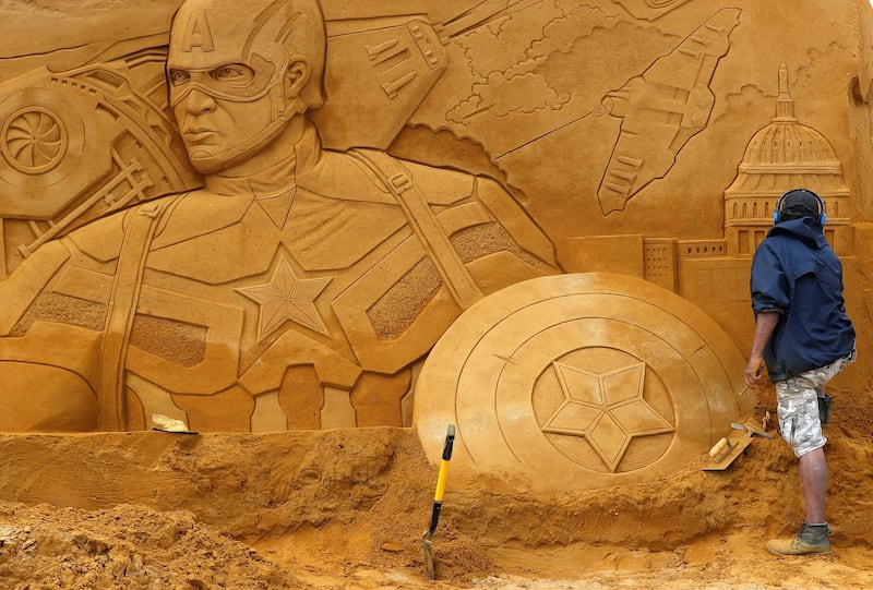 A sand carver works on a Captain America sculpture. Yves Herman / Reuters