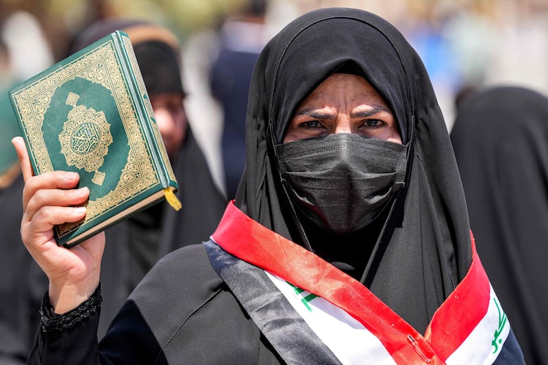 A woman holds the Quran in Kufa, Iraq, in protest after an activist desecrated a copy of the holy book for a second time in Sweden. AFP
