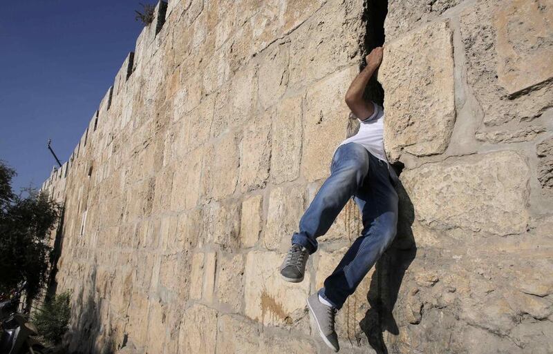 A Palestinian slips through an opening in Jerusalem’s Old City wall as he heads to visit a grave at a cemetery on Eid Al Fitr on July 28, 2014. Ammar Awad/Reuters