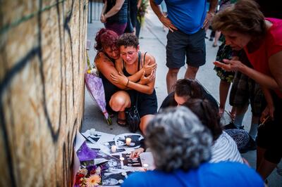 Desirae Shapiro, 19, next to wall kneeling at right, and her mother, Gina Shapiro, friends of 18-year-old Danforth shooting victim Reese Fallon, mourn while visiting a makeshift memorial, Monday, July 23, 2018, in Toronto, remembering the victims of the shooting on Sunday. (Mark Blinch/The Canadian Press via AP)