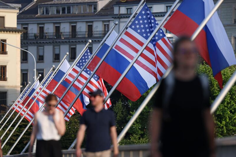 People walk under Russian and American flags on a bridge in the city center of Geneva. Getty Images