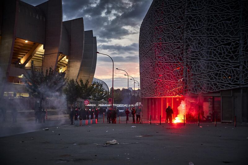 A flare lands near French riot police outside PSG's Parc de Princes stadium. Getty