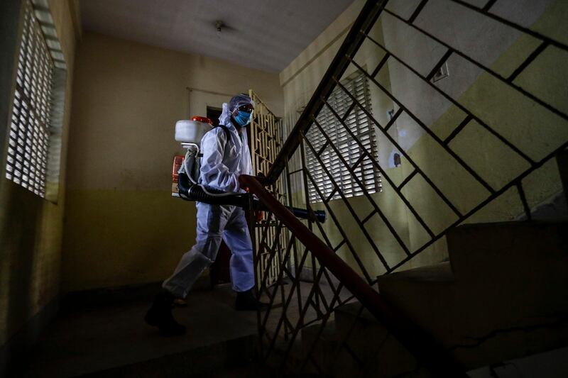 A civic staff in protective suit disinfects the staircase of an apartment in Kolkata, India. AP Photo