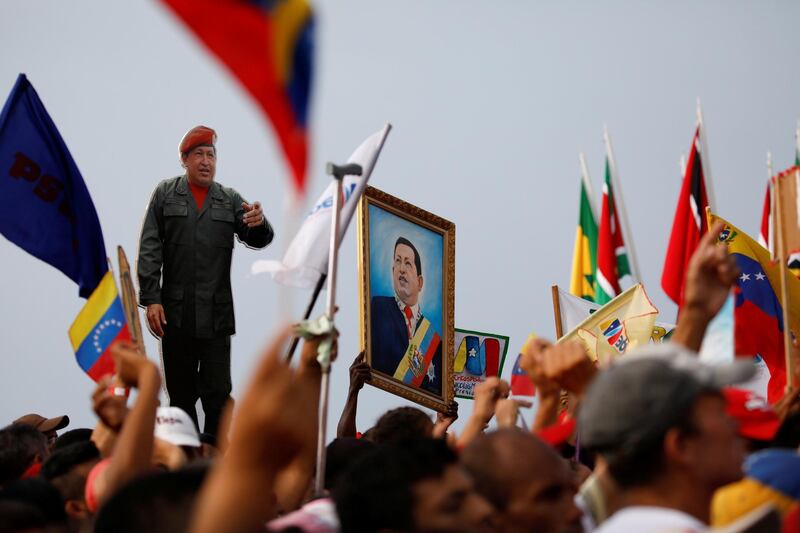 Supporters of Venezuela's President Nicolas Maduro - holding a cardboard cut-out and a painting depicting Venezuela's late President Hugo Chavez - attend a campaign rally in La Guaira, Venezuela. Carlos Garcia Rawlins / Reuters