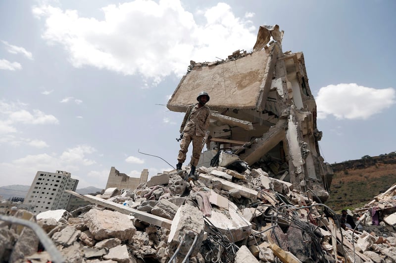 TOPSHOT - A Yemeni soldier stands on the debris of a house, hit in an air strike on a residential district, in the capital Sanaa on August 26, 2017.
Children were among at least 14 people killed in an air strike that toppled residential blocks in Yemen's capital Sanaa on Friday, witnesses and medics said. / AFP PHOTO / MOHAMMED HUWAIS