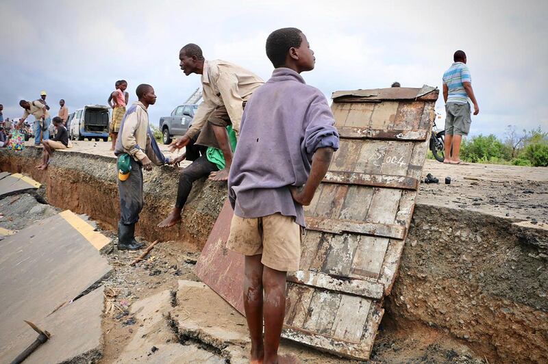 Locals stand on a damaged section of the road between Beira and Chimoio in Nhamatanda district, central Mozambique. AFP