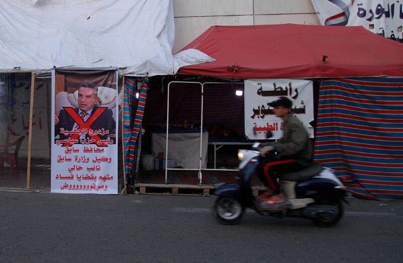 A motorbike passes by a defaced picture of Prime Minister-designate Adnan Al-Zurfi in Tahrir Square, Baghdad, Iraq, Thursday, March 19, 2020. Iraq's president named Al-Zurfi as prime minister-designate, following weeks of political infighting. (AP Photo/Khalid Mohammed)