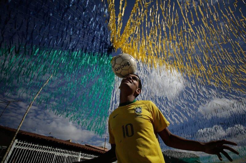 Joao Paulo, 16, plays with a football in the street decorated for the upcoming 2014 World Cup in a suburb outside Brasilia, Brazil on Wednesday. Eraldo Peres / AP / June 4, 2014