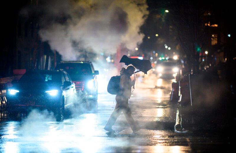 A man makes his way amid smoke from a steam pipe during rainfall in the evening hours in New York City. AFP