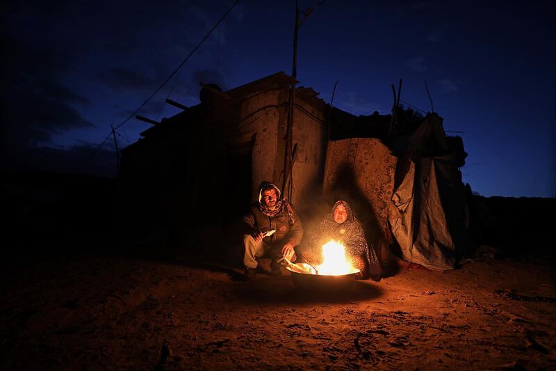 epa06970143 (FILE) - A Palestinian refugee couple warm themselves by a fire near their house during a cold weather in Khan Younis refugee camp in the southern Gaza Strip, 19 January 2018 (reissued 25 August 2018). According to media reports on 25 August 2018, the United States cut over 200 million US dollar in aid to Palestinians in the West Bank and Gaza Strip. US President Donald Trump ordered the State Department to direct the funds to 'high priority projects elsewhere.' The move comes after the US State Department suspended 65 million US dollar in aid to the United Nations Relief and Works Agency for Palestine Refugees in the Near East (UNRWA).  EPA/MOHAMMED SABER