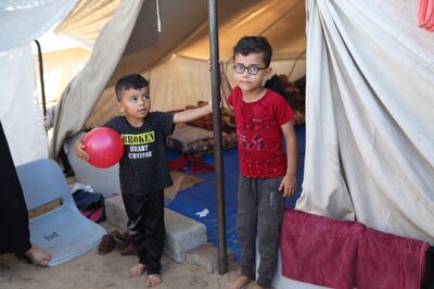 Oday Obied, aged seven, right, outside his temporary shelter. Rakan Abed El Rahman for The National