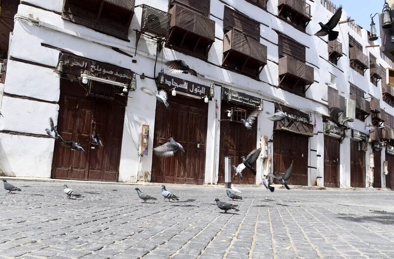 Pigeons fly around closed shops in the old town of Saudi Arabia's Red Sea coastal city of Jeddah on April 2, 2020. AFP
