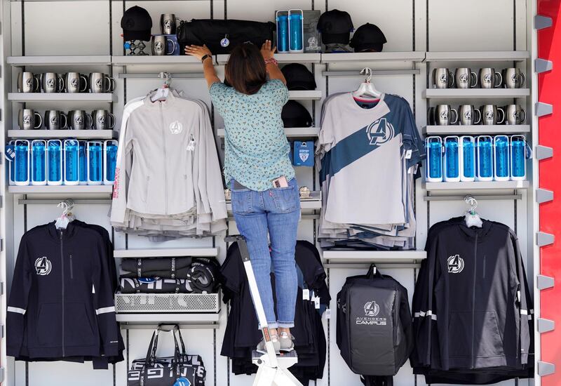 A worker arranges merchandise at one of the gift shops on site at the Avengers Campus. AP