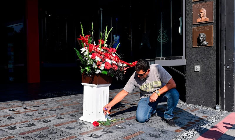 Van Halen fan George Salon leaves momentoes, which include flowers, a rose, guitar picks and a cigarette, on the handprints at the Guitar Center in Hollywood, California of late rock guitarist Eddie Van Halen on October 6, 2020.  AFP