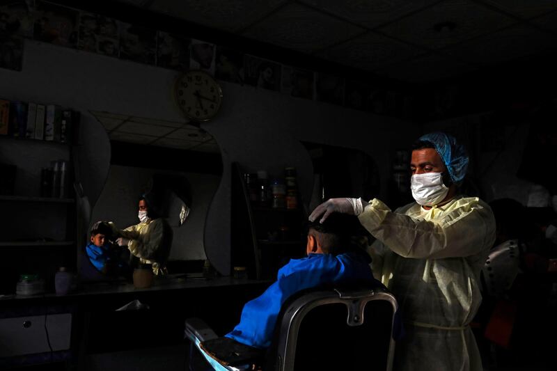 A hairdresser wearing a protective suit gives a customer a haircut at a barber shop ahead of Eid Al Fitr, in Sanaa, Yemen, May 18, 2020. EPA