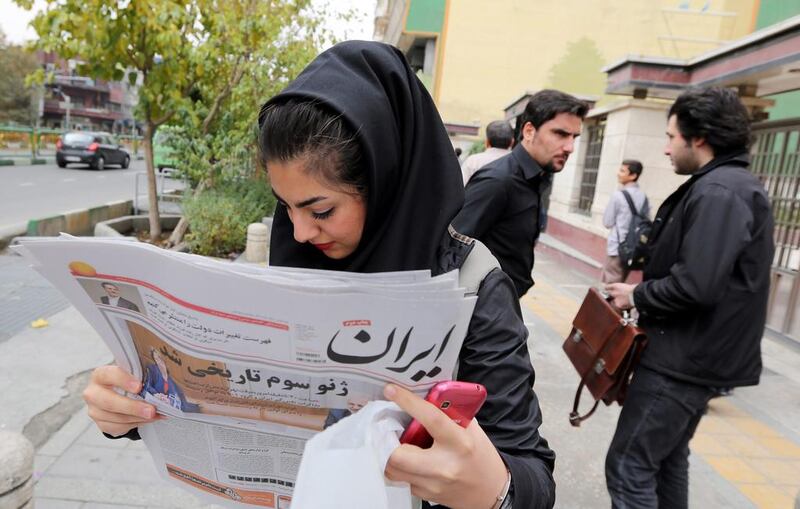 An Iranian girl reads a copy of the Iran newspaper with a headline translating 'Third Geneva was historical' outside a kiosk in Tehran. Abedin Taherkenareh / EPA

