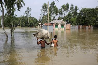 People move along a flooded area with their belongings in Gaibandha, Bangladesh, July 19, 2019. Reuters