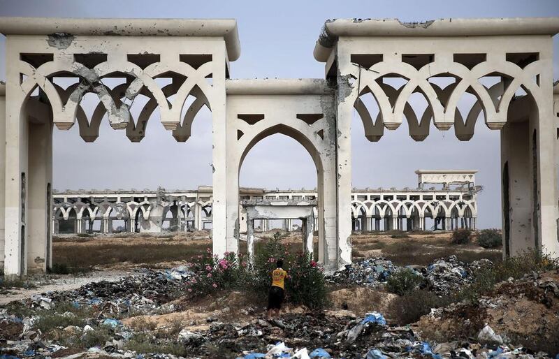 This picture taken on August 18, 2014 shows a Palestinian boy picking flowers in front of the destroyed and deserted main gate of Gaza Strip’s former international airport in the southern town of Rafah. As the ceasefire takes hold, Gazans are starting to dream again of the possibility of the airport's reopening. Thomas Coex/AFP Photo