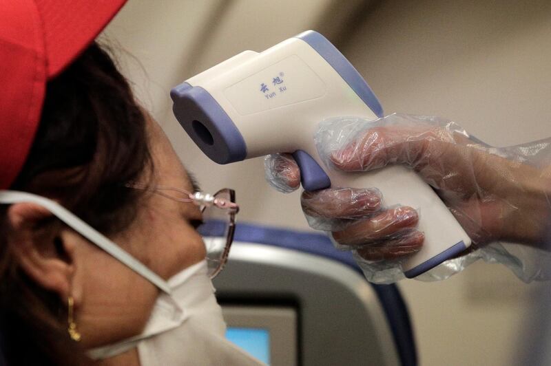 A stewardess takes the temperature of passenger as a preventive measure for the coronavirus on an Air China flight from Melbourne to Beijing before it landed at Beijing Capital International Airport in China. AP Photo