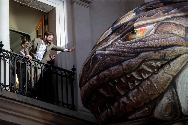 Chile's President Gabriel Boric touches 'Saurian, an inflatable dinosaur, at La Moneda Presidential Palace in Santiago. AFP