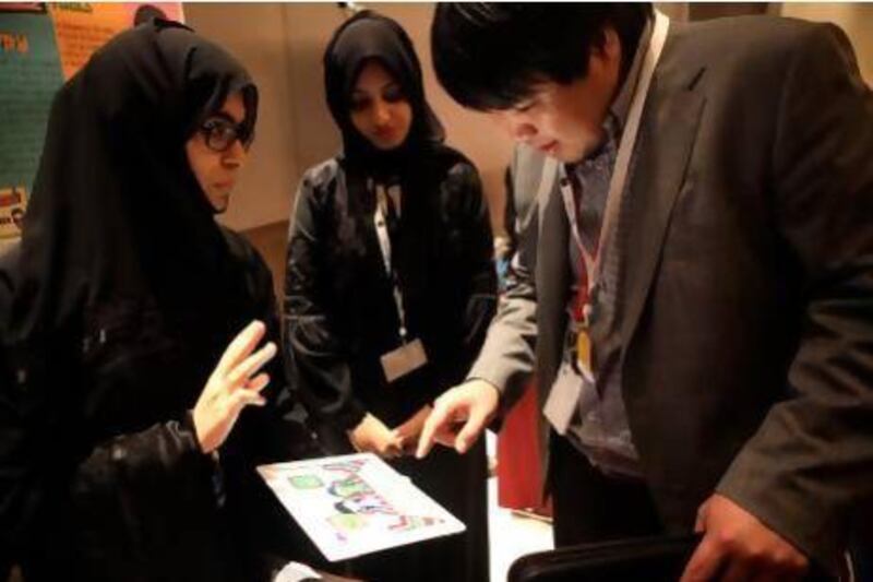 Kalthoom Al Awar, left, and Nujood Al Sayari from UAE University show their Tabkh Time app to Dr Paul Yoo from Khalifa University during the Mobile Application Contest in Abu Dhabi yesterday. Sammy Dallal / The National