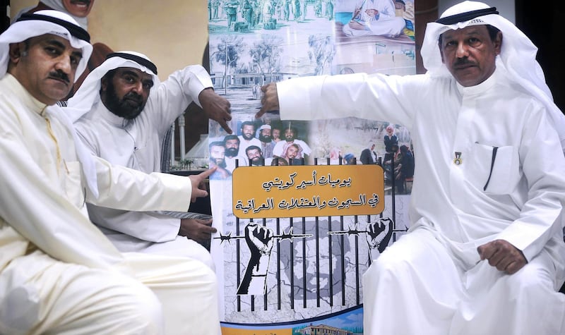 Kuwaiti former prisoners of war (RtoL) Nasser Salmeen, Abdulwahad al-Nafah and Abdullah al-Awadhi shows theirs faces on a picture taken during their captivity in an Iraqi prison on August 2, 2015 in Kuwait City at the Kuwait House for National Works Museum. The three were released on March 1991, nearly a month after Kuwait's liberation. Kuwait marks on August 2, 2015 the 25th anniversary of the 1990-1991 Iraqi Invasion.  AFP PHOTO / YASSER AL-ZAYYAT (Photo by YASSER AL-ZAYYAT / AFP)