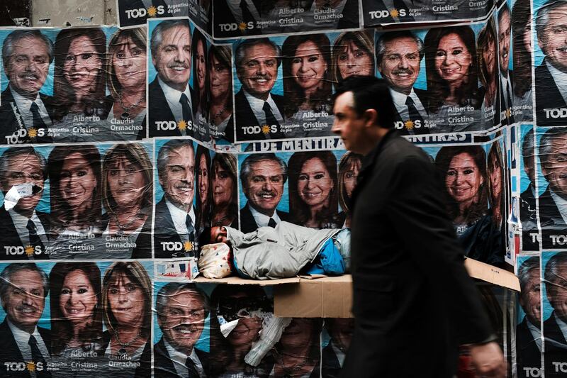 BUENOS AIRES, ARGENTINA - OCTOBER 28: A homeless man sleeps under posters of newly elected president Alberto Fernandez and his running mate Cristina Fernández de Kirchner as people walk through a central business district  the morning after populist was declared the winner in the presidential elections on October 28, 2019 in Buenos Aires, Argentina. The Populist-leaning Fernandez beat out business-friendly incumbent Mauricio Macri in the election that could will have huge consequences for the South American country. With a sharp drop in the peso, high unemployment and rising inflation, Argentines are looking for a leader to steer the economy towards stabilization. (Photo by Spencer Platt/Getty Images)