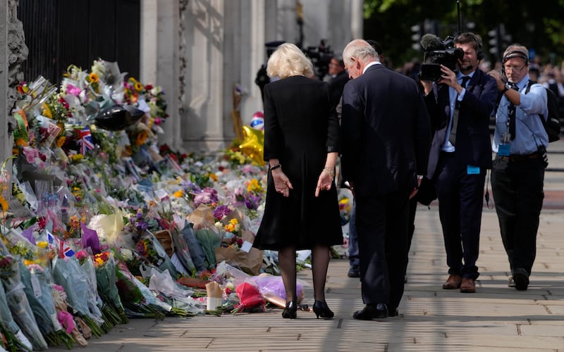 King Charles and the queen consort read messages left by mourners at Buckingham Palace in London. Queen Elizabeth II, Britain's longest-reigning monarch and a rock of stability through much of a turbulent century, died on Thursday, after 70 years on the throne. She was 96.  AP