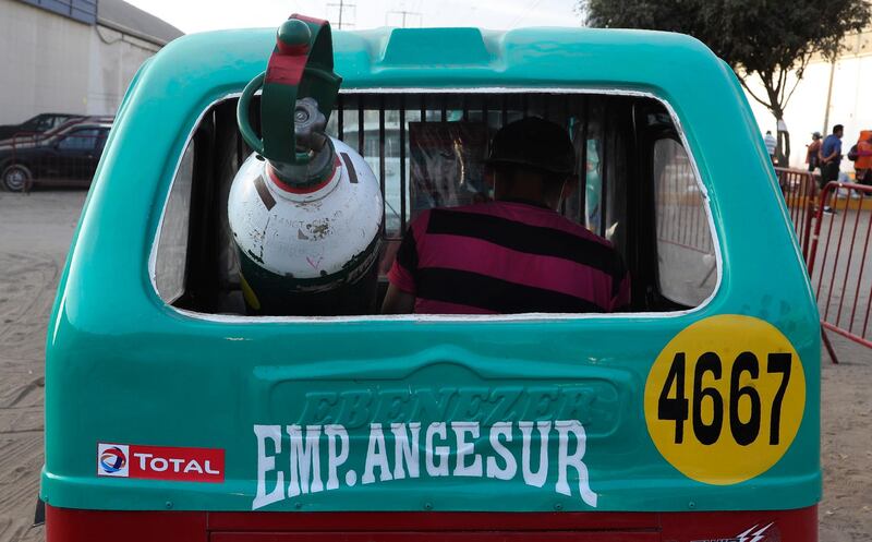 A man leaves in a moto-taxi with his full oxygen tank, after waiting for three days for a refill in the poor area of Villa El Salvador, in Lima, Peru. AP Photo