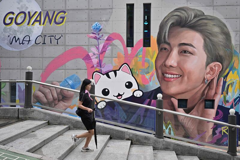 A woman walks past a mural depicting RM, a member of K-pop group BTS, in Goyang, northwest of Seoul, on June 15, 2022.  (Photo by Anthony WALLACE  /  AFP)