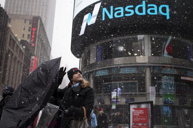 FILE PHOTO: A woman's umbrella turns inside out as she walks past the Nasdaq MarketSite during a snow storm in Times Square, New York, March 20, 2015.   REUTERS/Adrees Latif/File Photo